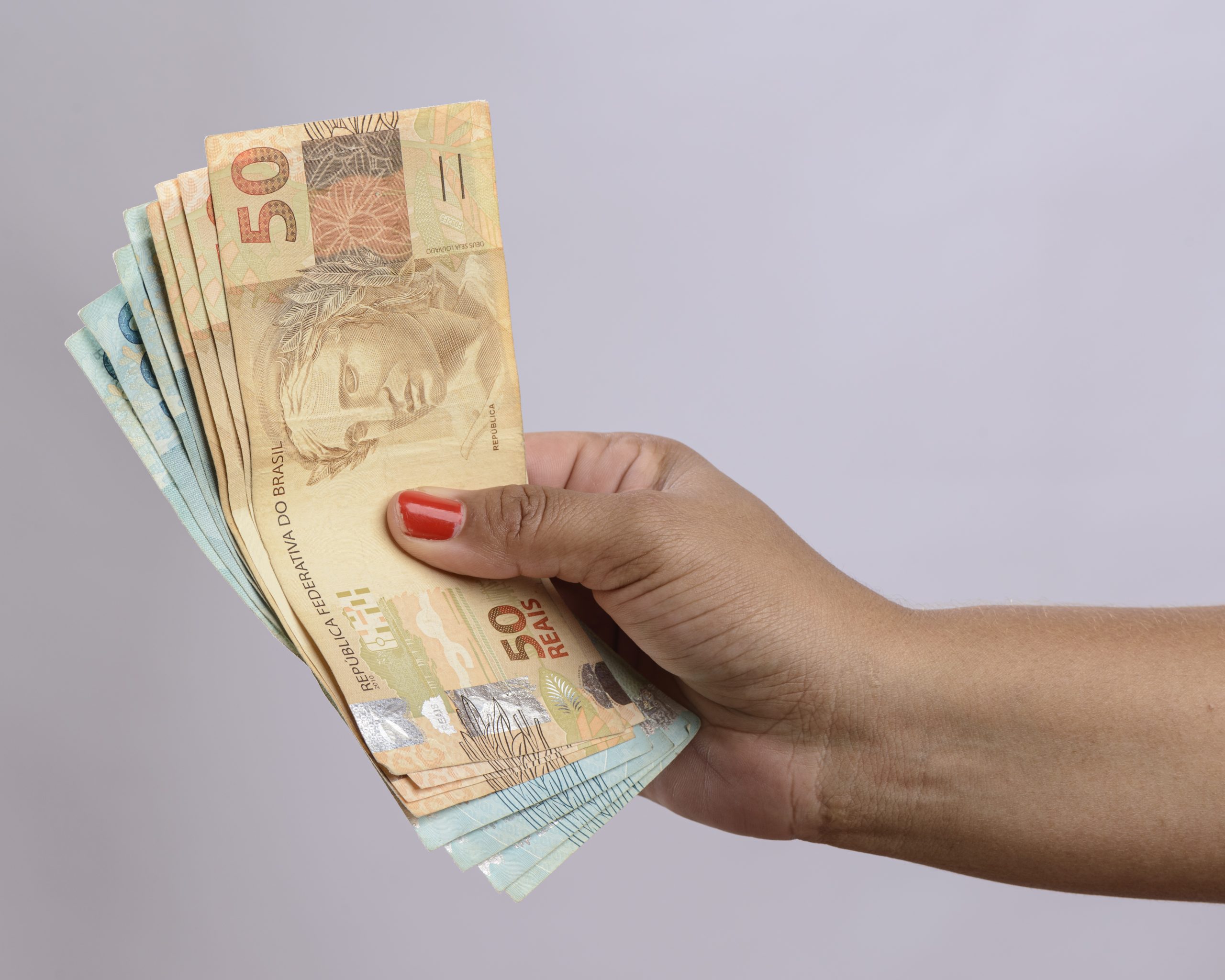 Mão segurando o dinheiro seiscentos reais moeda brasileira no fundo branco
